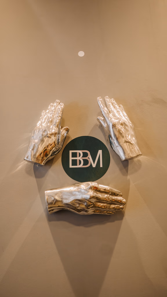 Elementos decorativos com mãos escultóricas e identidade visual da BBM Advocacia em ambiente corporativo do escritório.